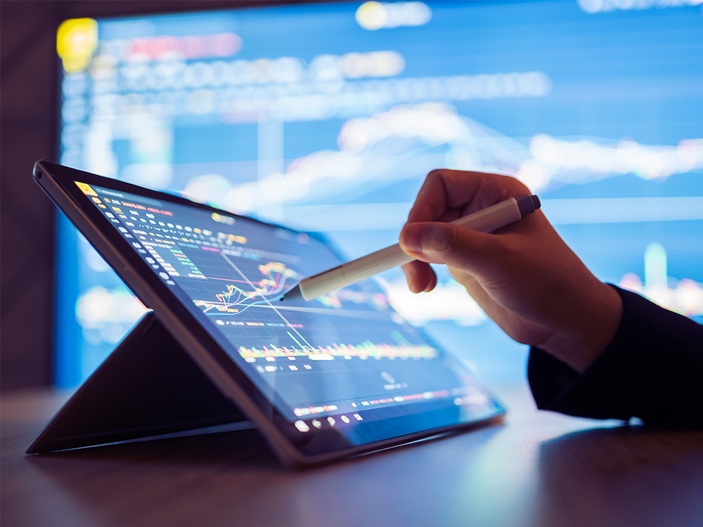 hand writing on a tablet in front of a screen